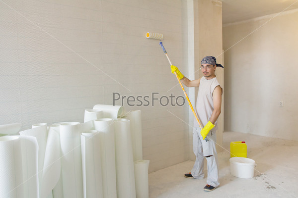 Home decoration. Worker painting wallpaper with painting roller