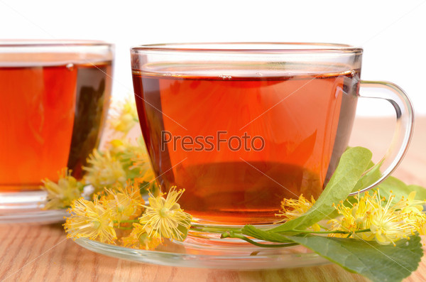 Herbal tea in glass cups with linden flowers on a wood table on white background
