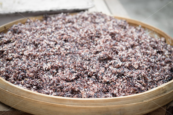 Cooked steam black rice in big wooden plate dish with shallow depth of field