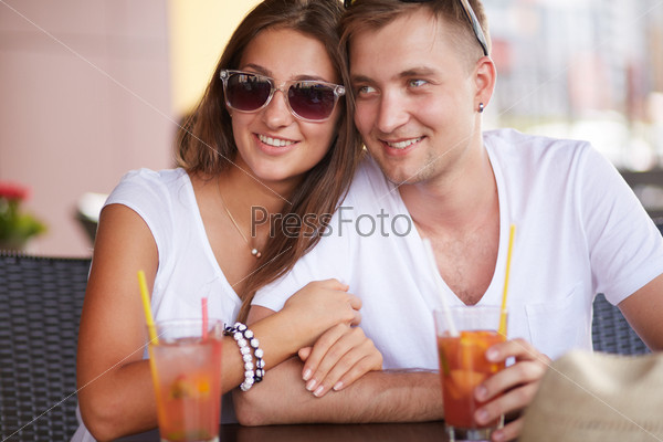 Young guy and his girlfriend sitting in cafe on summer day, stock photo