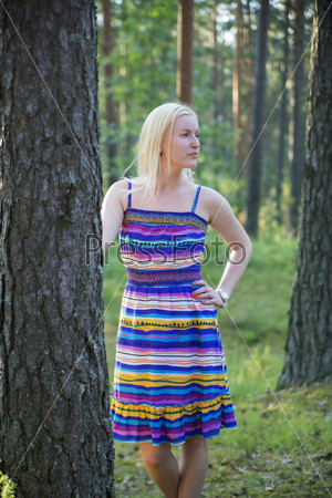 Woman in lined dress behind pine tree stem