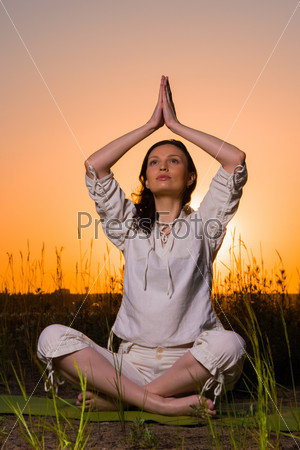 Yoga woman during sunset meditating against the sun outdoors