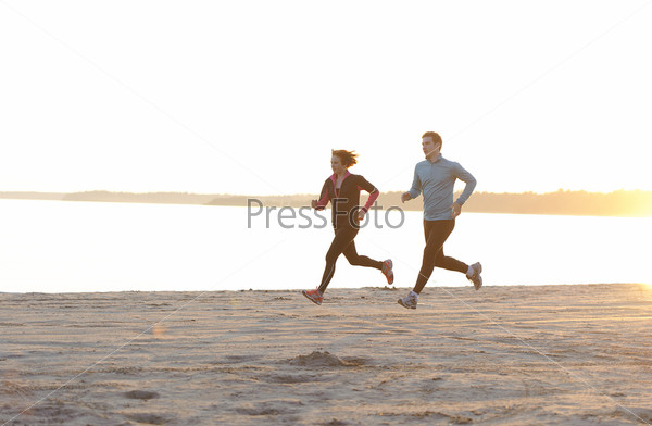 Young man and woman running along the waterfront