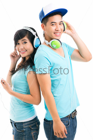 Two young people listening to music, looking at camera and smiling