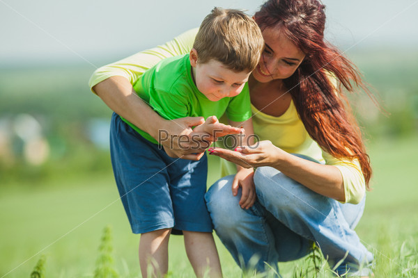 Mom and son consider a ladybug on a palm