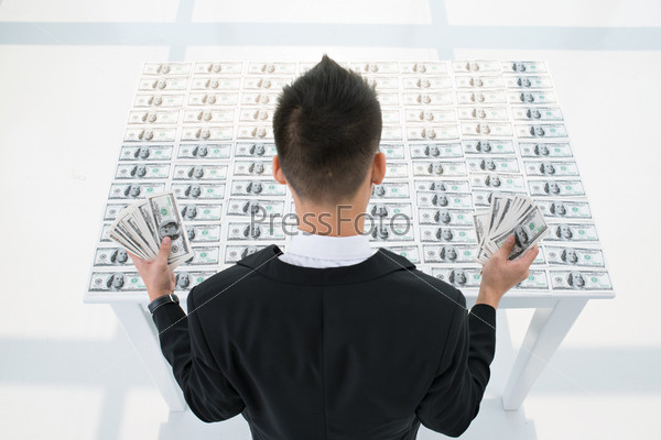 Back view of a businessman behind a money table