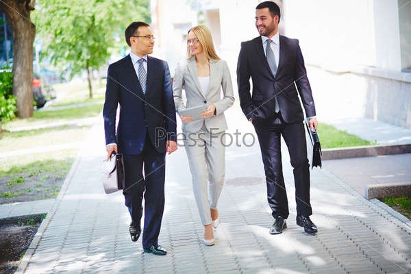 Image of elegant colleagues walking and discussing business matters on the move