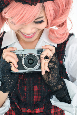 Vertical image of a fancy-dressed girl taking a picture with a vintage camera