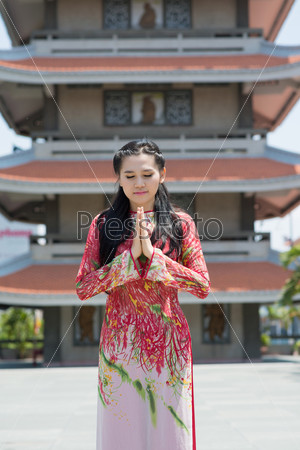 Vertical image of a buddhist praying woman outside