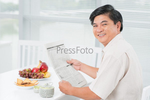 Portrait of a cheerful mid-age man having a snack and a reading