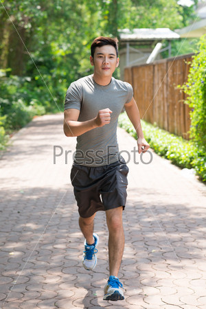 Full-length portrait of a male jogger running along the path