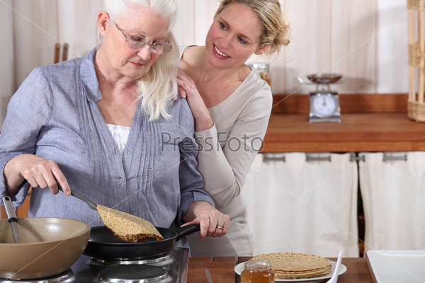 daughter helping her senior mother in the kitchen