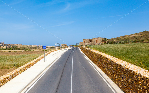 Mediterranean landscape. road, rail fence and a field on a clear day