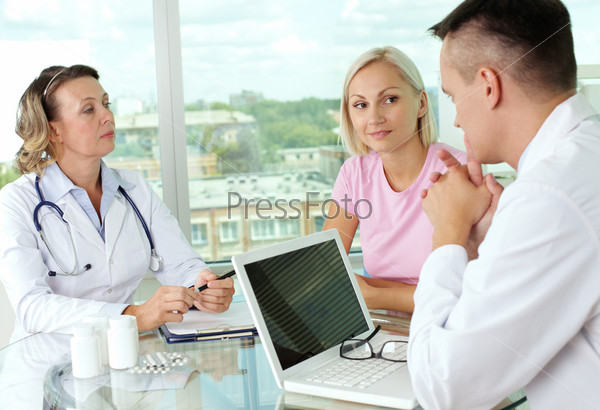 Portrait of two doctors and patient discussing new method of medical treatment, stock photo
