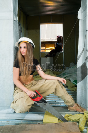 Woman construction worker in hard hat with handsaw