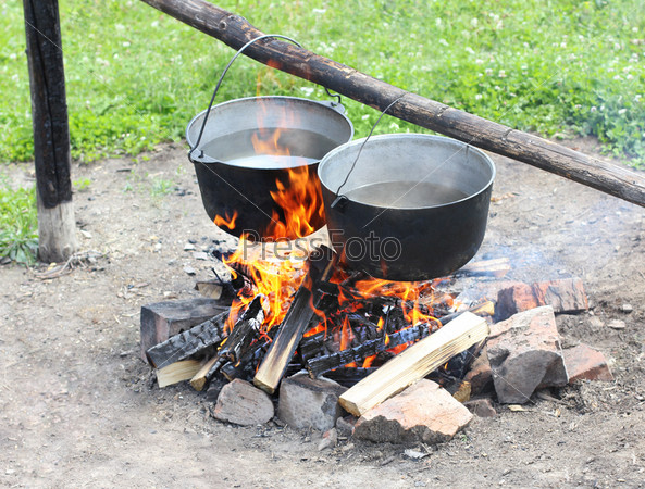 Two pot hanging over the fire. Preparing food on campfire in wild camping.