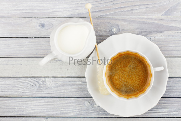 Black coffee and cream jug on a wooden table