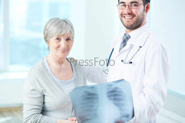 Senior patient and radiologist with x-ray looking at camera in hospital