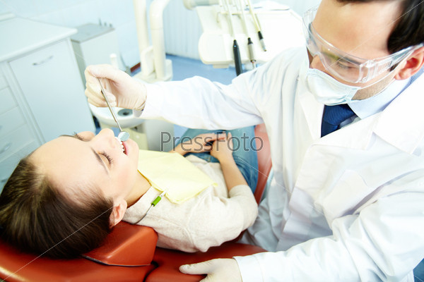 Smiling woman sitting in dentistÃ?Â¢??s chair while doctor examining her teeth