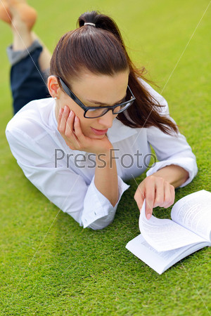 Young student woman reading a book and study in the\
park