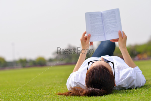 Young student woman reading a book and study in the park, stock photo
