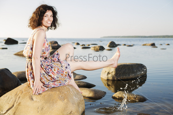Barefoot woman squirts water drops with shaven leg