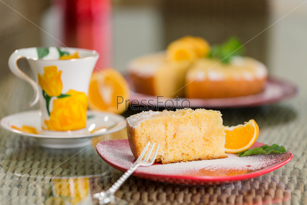 Slice of freshly cooked orange cake with spoon, sugar dusting, and nice background