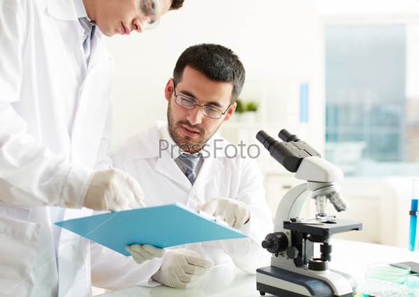 Two clinicians discussing medical document in laboratory