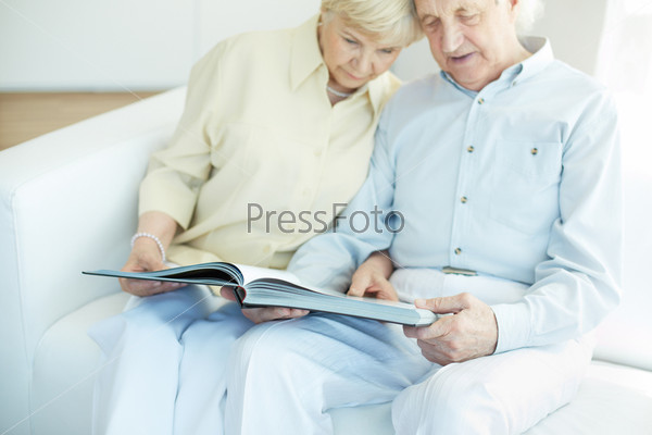 Portrait of a candid senior couple reading book at leisure