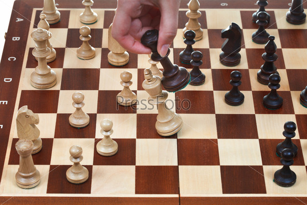 hand with black king knocks white king on chessboard in chess game