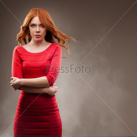 sexual woman portrait with flying hair wearing red dress over dark background, copy space