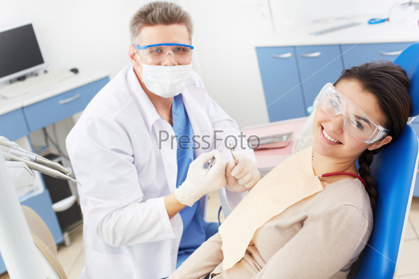 Happy girl in protective eyeglasses looking at camera with toothy smile at the dentistÃ?Â¢??s