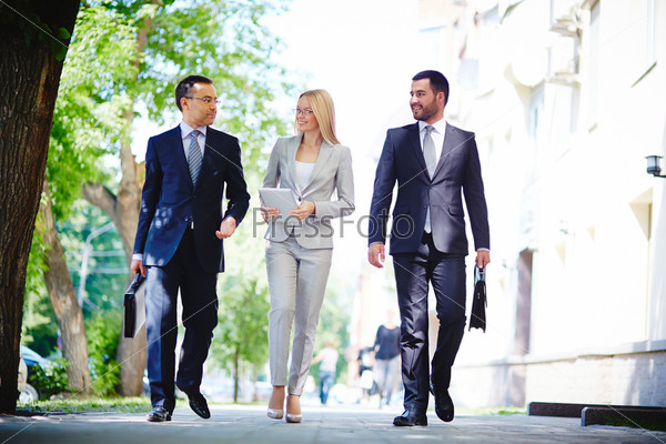Image of elegant colleagues walking and discussing business matters on the move