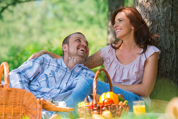 Adult couple picnicking in the park under the tree