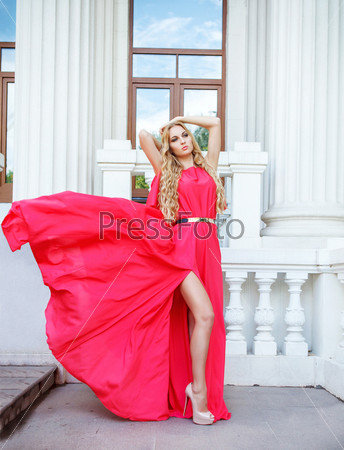 Beautiful blond woman in long red dress outdoors on the stairs
