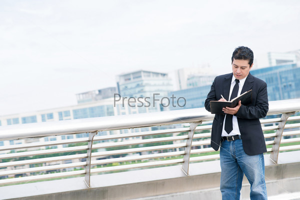 Copy-spaced image of a mid-aged businessman making notes in his notepad outside