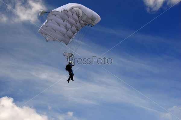 Skydiver moving down in high speed just before landing. Background with blue sky with clouds.