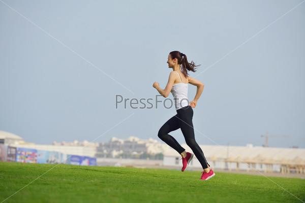 Running in city park. Woman runner outside jogging at morning\
with Dubai urban scene in background