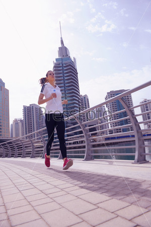 Running in city park. Woman runner outside jogging at morning\
with Dubai urban scene in background