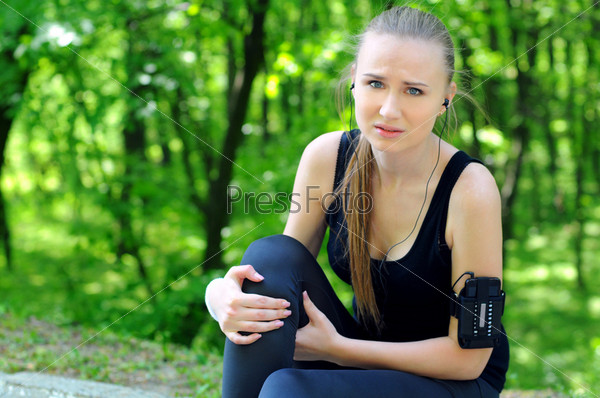 Sportswoman bended knee because of an ankle painful sprain injury. Female runner athlete lesion.