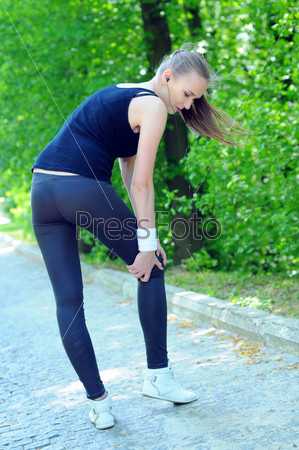 Sportswoman bended knee because of an ankle painful sprain injury. Female runner athlete lesion.