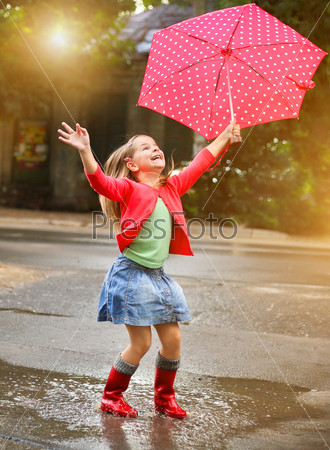 Child with polka dots umbrella wearing red rain boots