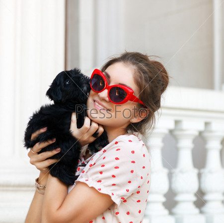 Happy young brunette woman hugging her lap dog puppy
