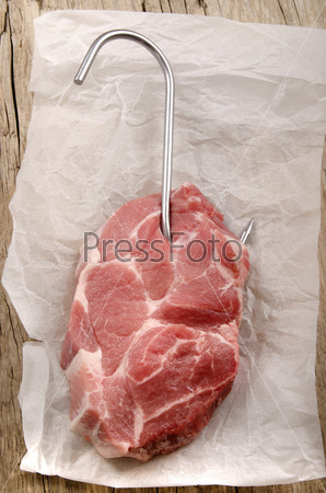pork shoulder steak with a butcher hook on paper