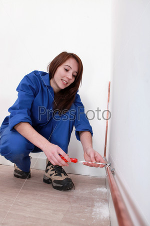 Tradeswoman fixing a copper tube against a wall