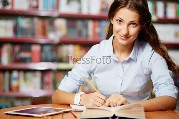 Portrait of clever student looking at camera while working in college library
