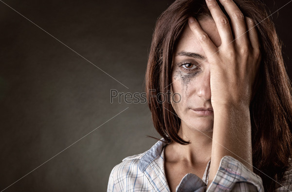 Young crying woman on a dark background, stock photo