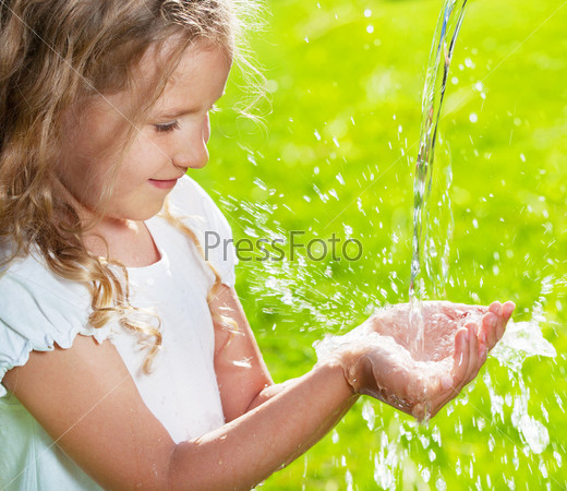 Stream of clean water pouring into children\'s hands. Child play with water