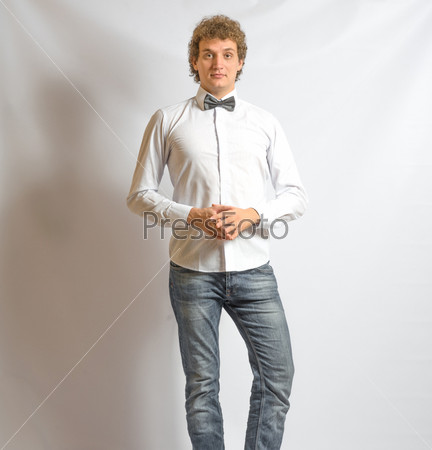 Young fashion male model wearing bow tie on gray