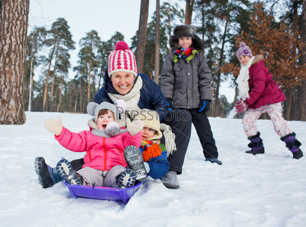 Four kids with mother is sledging in winter-landscape